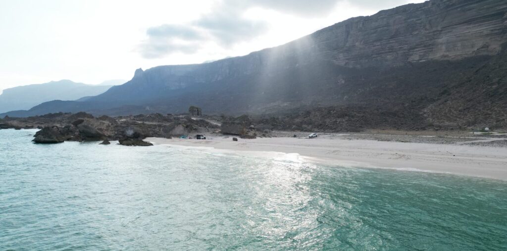 Panoramic coastal view of Al Fazayah Beach in Salalah, Oman with mountains and turquoise sea