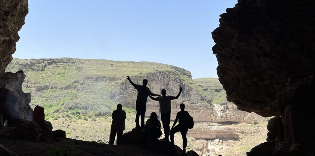 Hikers inside Teeq Cave in Salalah Oman overlooking mountain landscape and natural rock formations