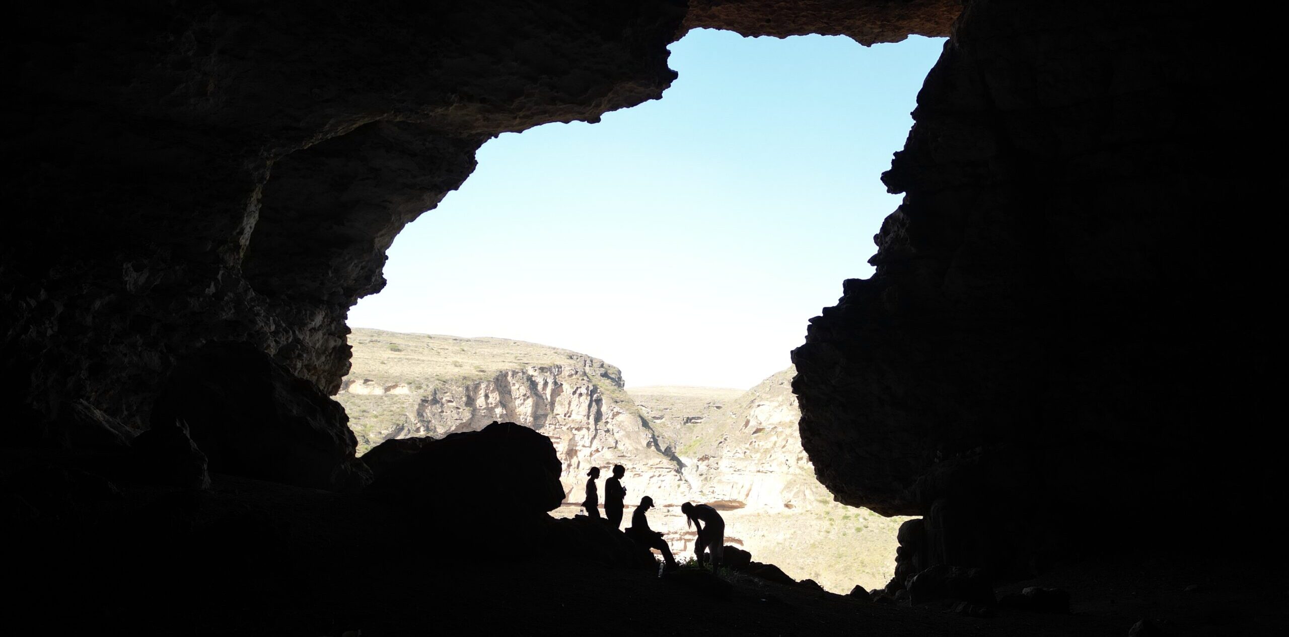 Hikers inside Teeq Cave in Salalah Oman overlooking mountain landscape and natural rock formations