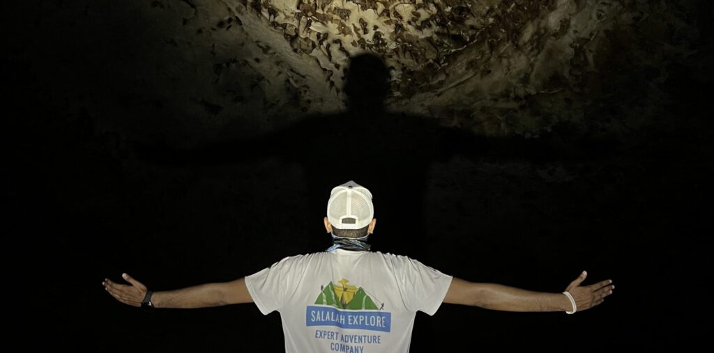 Hiker exploring Bat Cave in Nujab Valley Salalah Oman during guided hiking adventure tour
