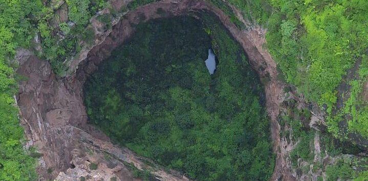 Aerial view of Tawi Atair Sinkhole in Salalah Oman surrounded by green landscape and dramatic rock formations