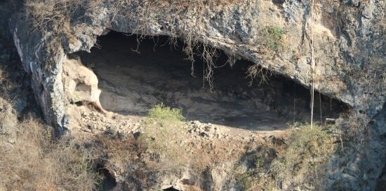 Entrance of Tawi Atair Sinkhole in Salalah Oman with rocky cliffs and adventure ropes setup