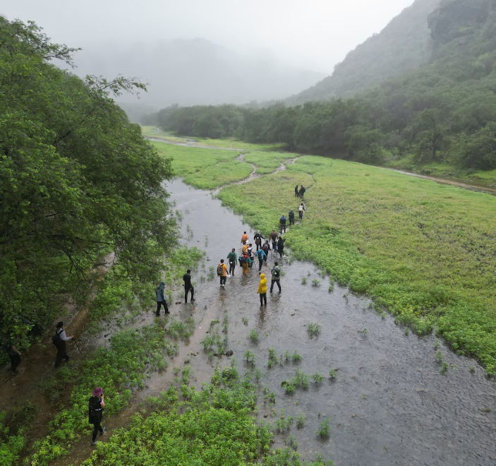 Group hiking at Wadi Jarziz in Salalah, Oman during Khareef season with green valley and stream