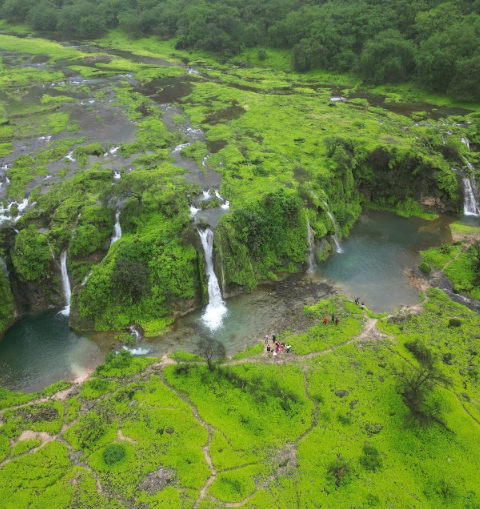 Aerial view of waterfalls in Salalah, Oman with green landscape and natural pools