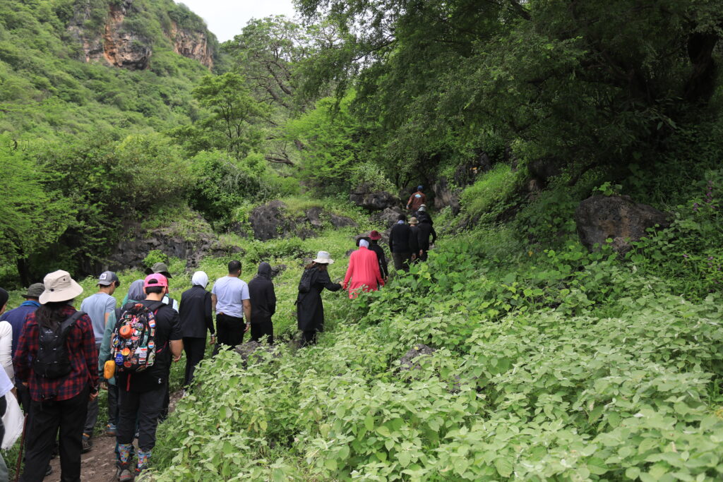Guided hiking group walking through lush green mountains in Salalah Oman during adventure tour